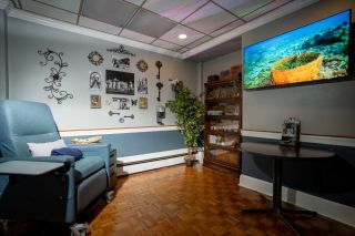 Interior of a Therapeutic Infusions clinic room with a comfortable medical recliner chair, a side table with a medical monitor,  embodying the tranquility and professionalism of our ketamine therapy and vitamin infusion services